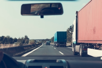 Car driving on the freeway next to a semi truck