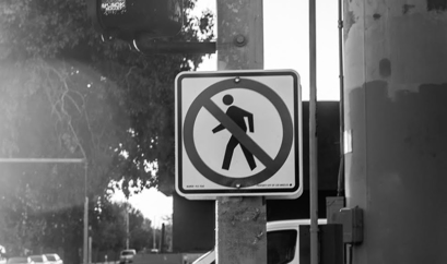 A black and white no pedestrian crossing sign